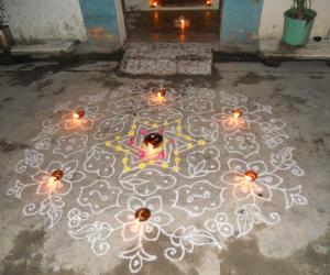 Karthigai kolam in white with deepam & flowers.