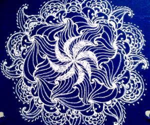 White swirling flower- a freehand rangoli with kolamavu on a blue plastic cover.